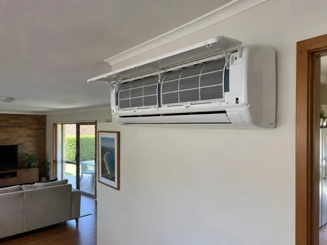 Open split system air conditioner on a cream wall in a living room with timber trim in Bundall